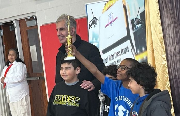 A small group of students, with one holding a trophy.